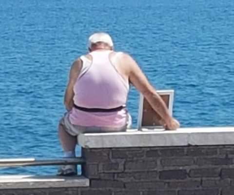 Osserva il mare con la foto della moglie defunta, la storia d’amore che sta commuovendo il web