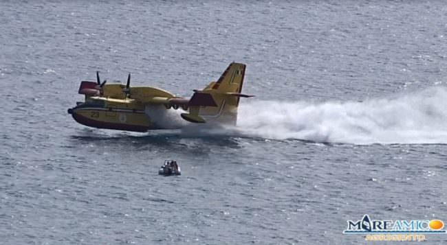 Divampa incendio: canadair sfiora gommone durante carico d’acqua – VIDEO