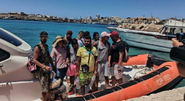 Occhiali da sole, cappelli e barboncino al guinzaglio. Sbarco “singolare” a Lampedusa: migranti-vacanzieri