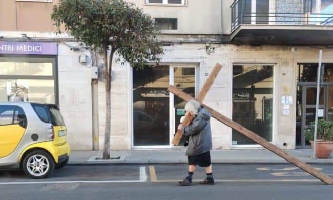 Passeggia per Siracusa con una grande croce sulle spalle: la foto dell’anziana fa il giro dei social